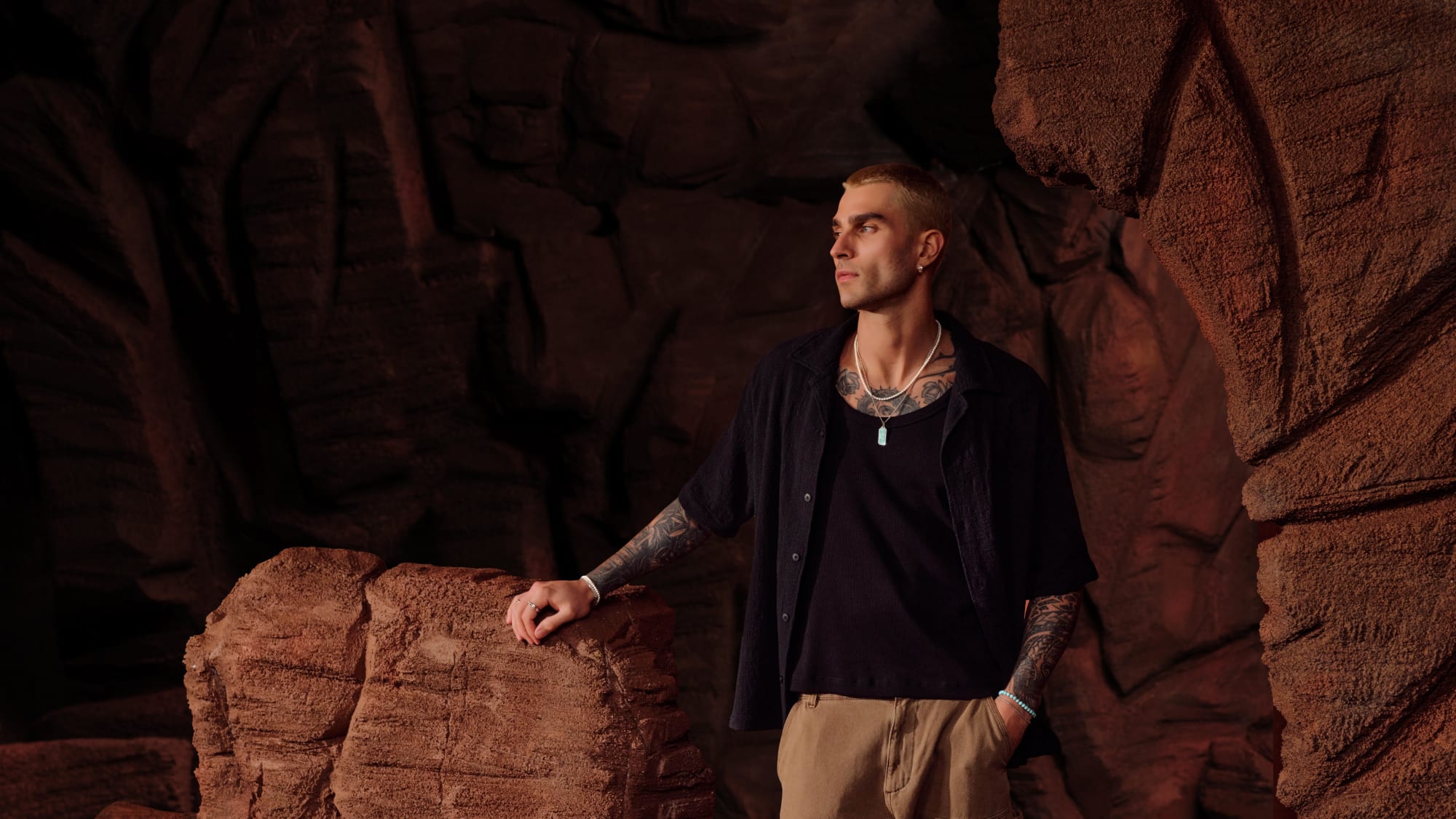 Model wearing a turquoise beaded bracelet and pendant poses in a rocky, desert scene.